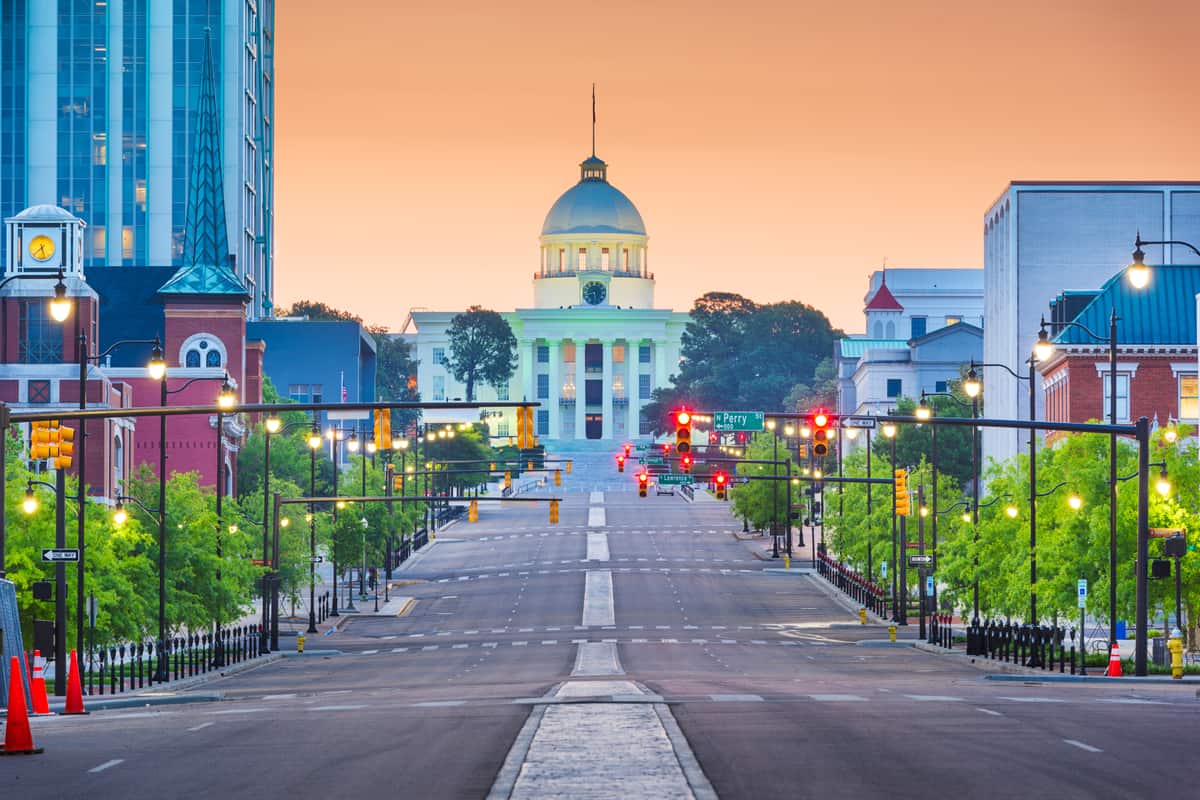 Dexter Avenue at dawn in Montgomery, Alabama, looking up the empty street to the domed Alabama State Capitol standing lit against an orange sky